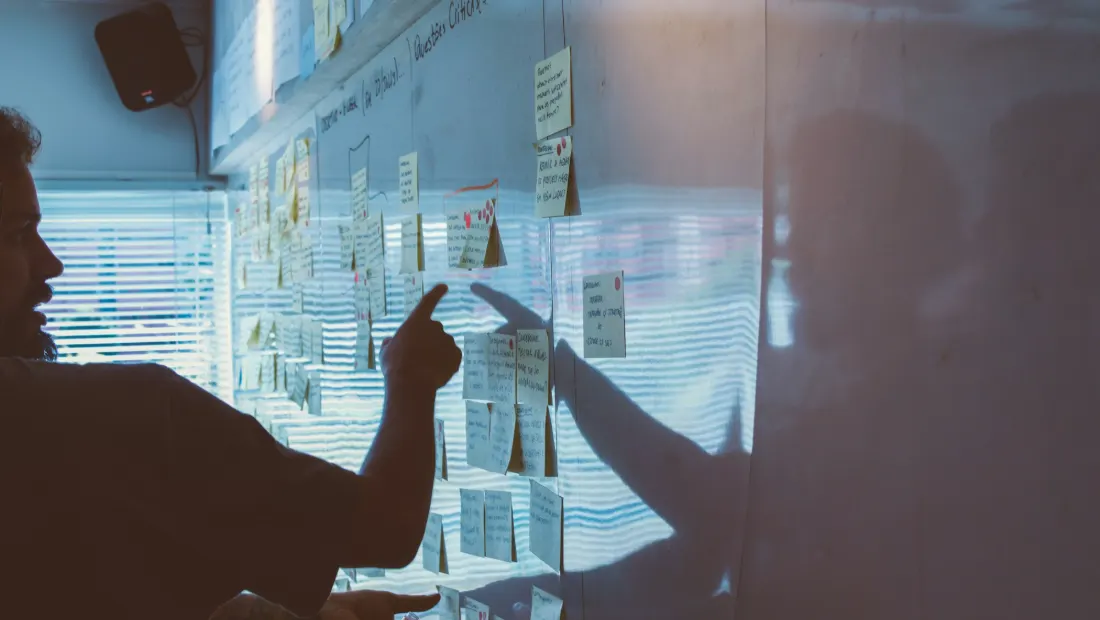 Person pointing at a strategy plan pinned to a wall