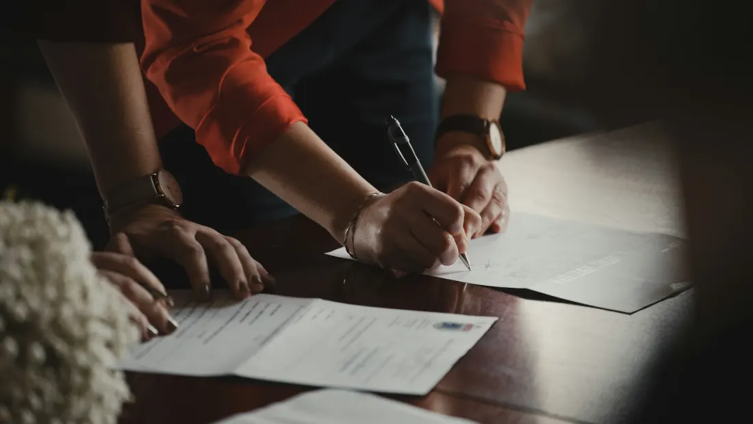 Person in an orange sleeve writing notes on paper