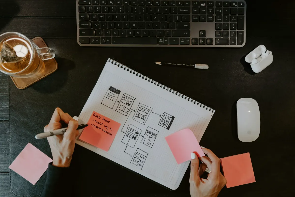 Person sketching wireframes on paper next to a keyboard
