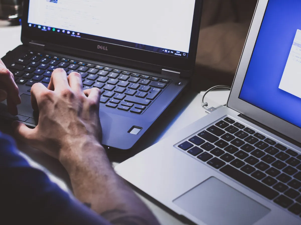 Developer working across two laptops while maintaining a website
